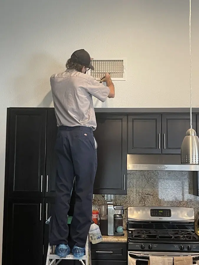 Technician inspecting an air vent during HVAC service in Riverton